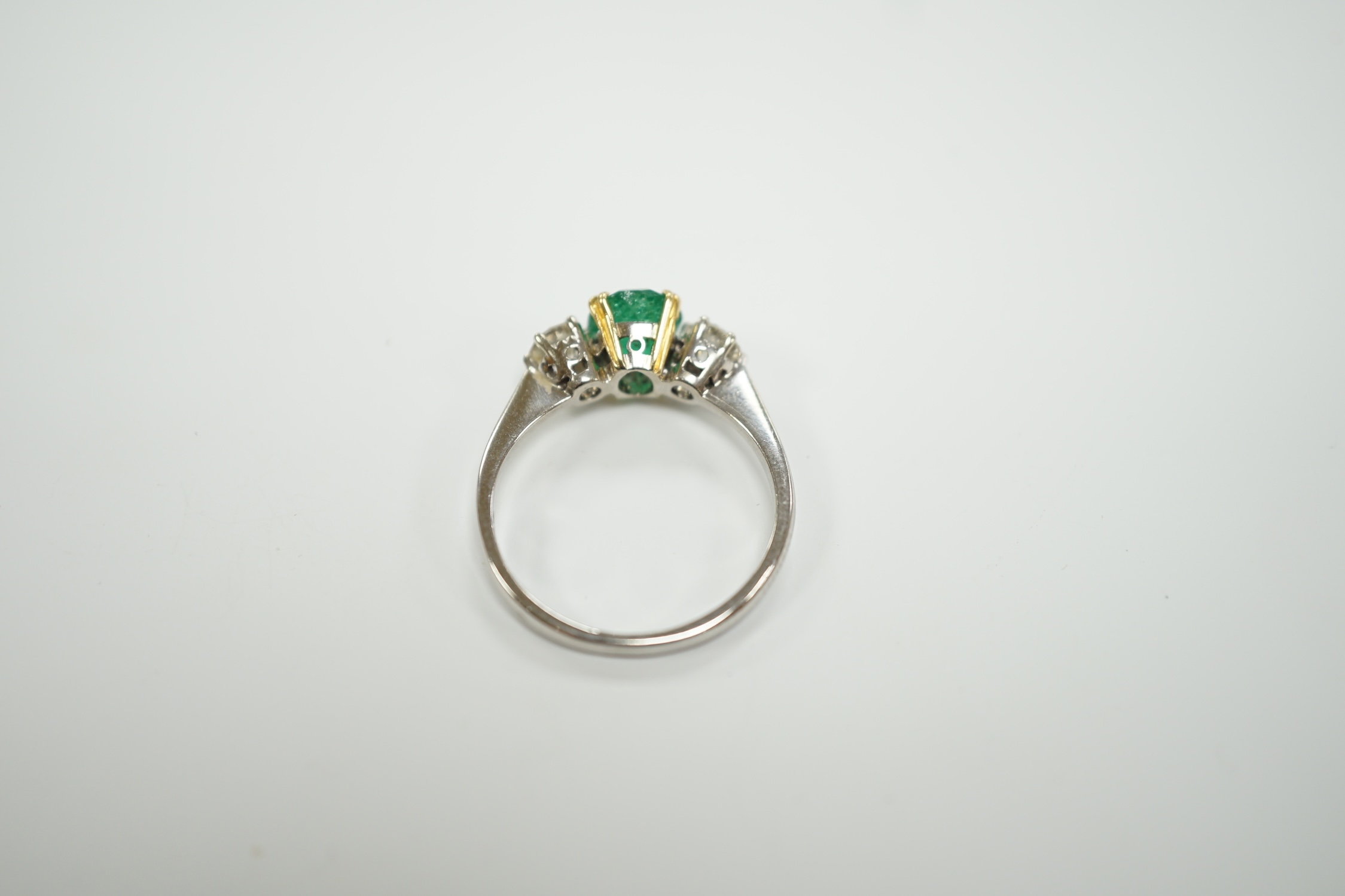 A 1970's 18ct white gold, single stone oval cut emerald and two stone diamond set ring, size P/Q, gross weight 3.2 grams.